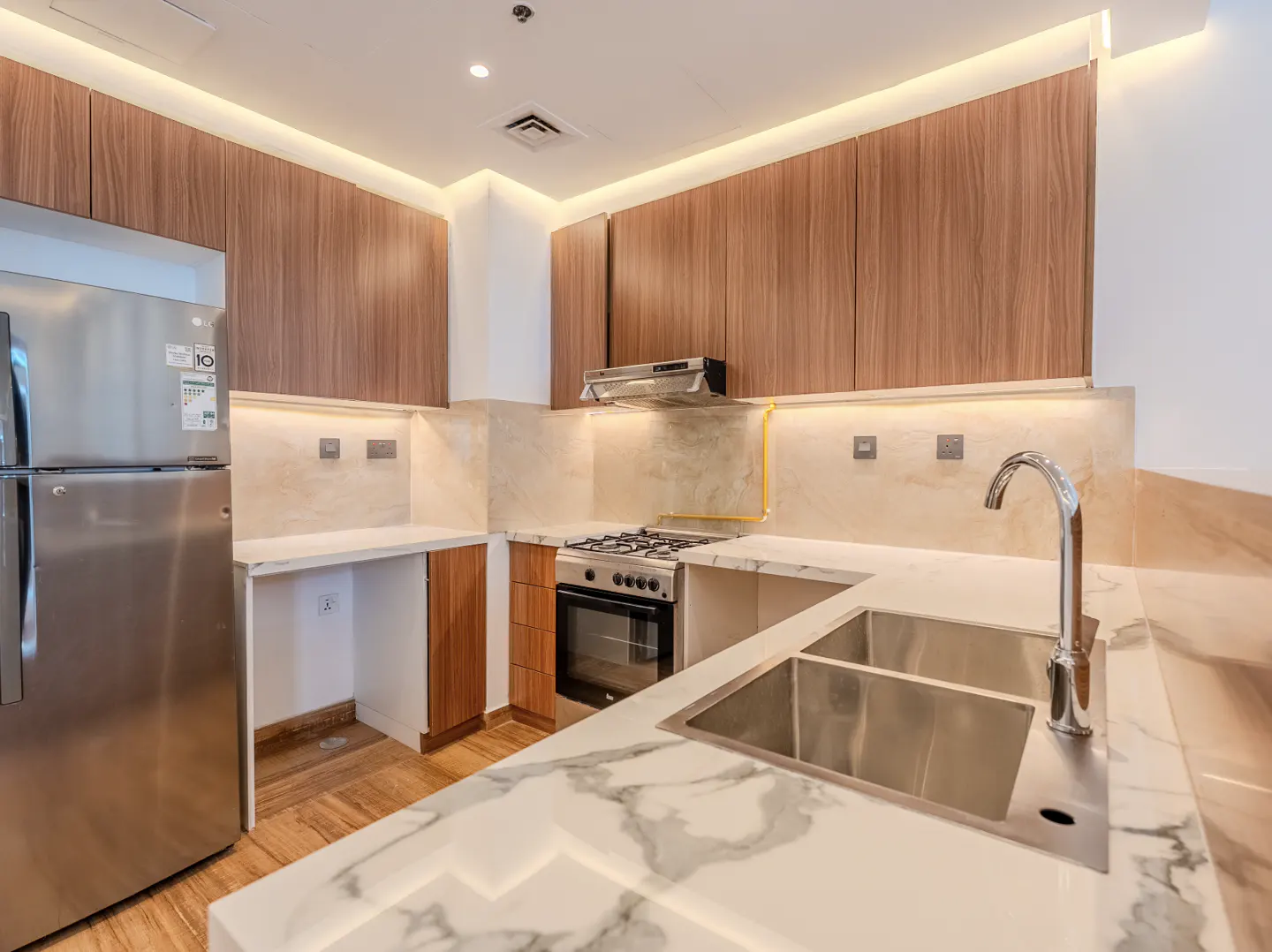 A modern kitchen with wood cabinets, marble countertops, and stainless steel appliances.