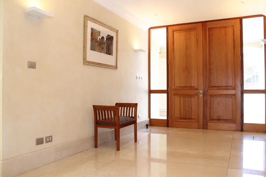 A bright foyer with a wooden bench, framed art, and double doors with sidelights.