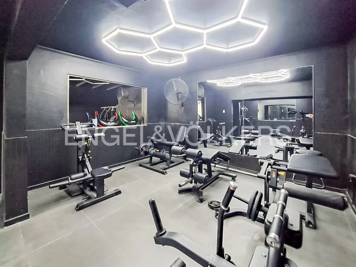 A modern gym with black walls, gray floors, and hexagon-shaped ceiling lights. Various weight machines are arranged throughout the space.
