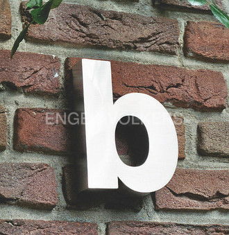 Close-up of a white lowercase "b" attached to a textured red brick wall with green leaves in the upper left corner.