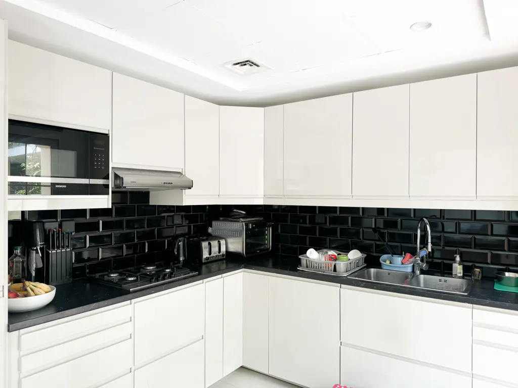Bright kitchen with white cabinets, black countertop and backsplash. Stainless steel sink, microwave, and appliances.