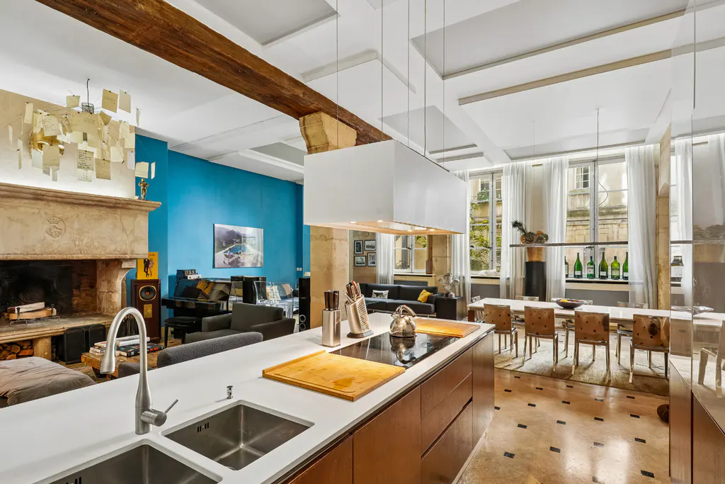 Open-concept living space with a kitchen island, fireplace, dining table, and seating area. The walls are blue and white.
