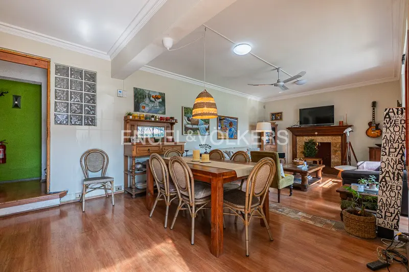 Open-concept living and dining area with wood floors, a dining table, and a fireplace.