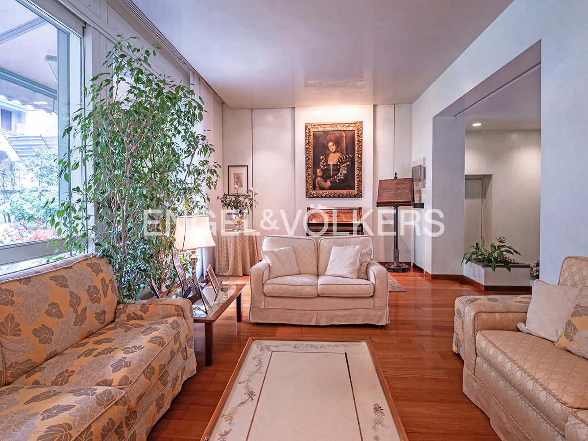 A bright living room with hardwood floors, two sofas, a large window, and a painting on the wall.