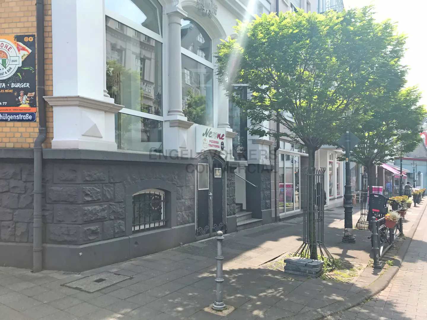 Exterior view of a commercial building with a "Newone Pizzeria Trattoria" sign, trees, and street lamps.