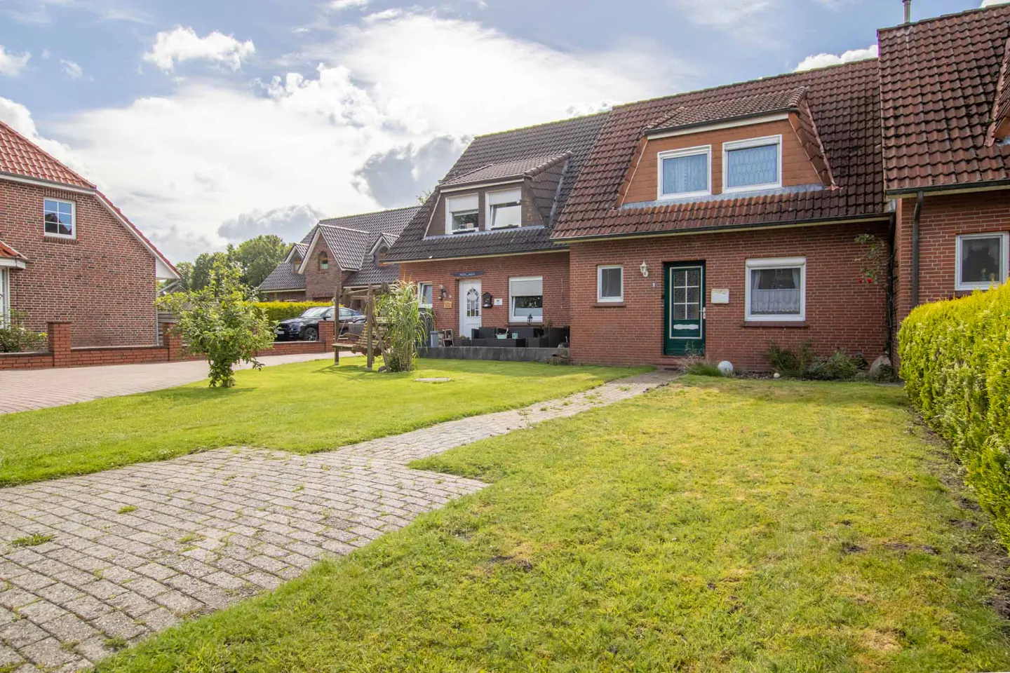Exterior view of a red brick house with a green lawn and a stone walkway.
