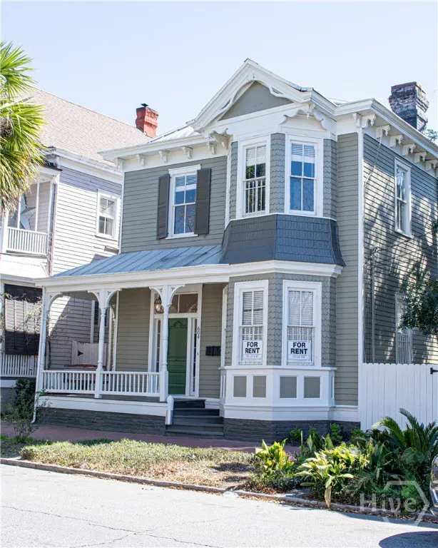 Two-story house with a porch and a green door. "For Rent" signs are in the windows.