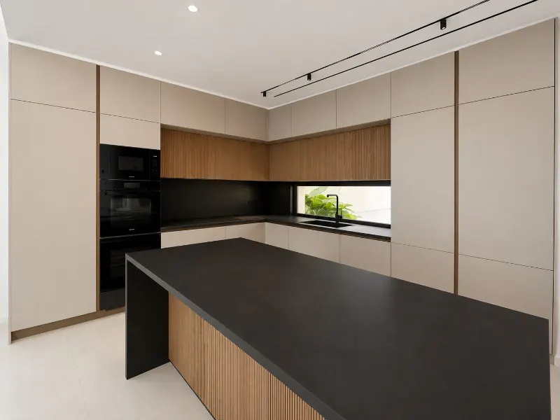 A modern kitchen with beige cabinets, wood accents, and a black countertop island. Black appliances and a window with greenery are visible.