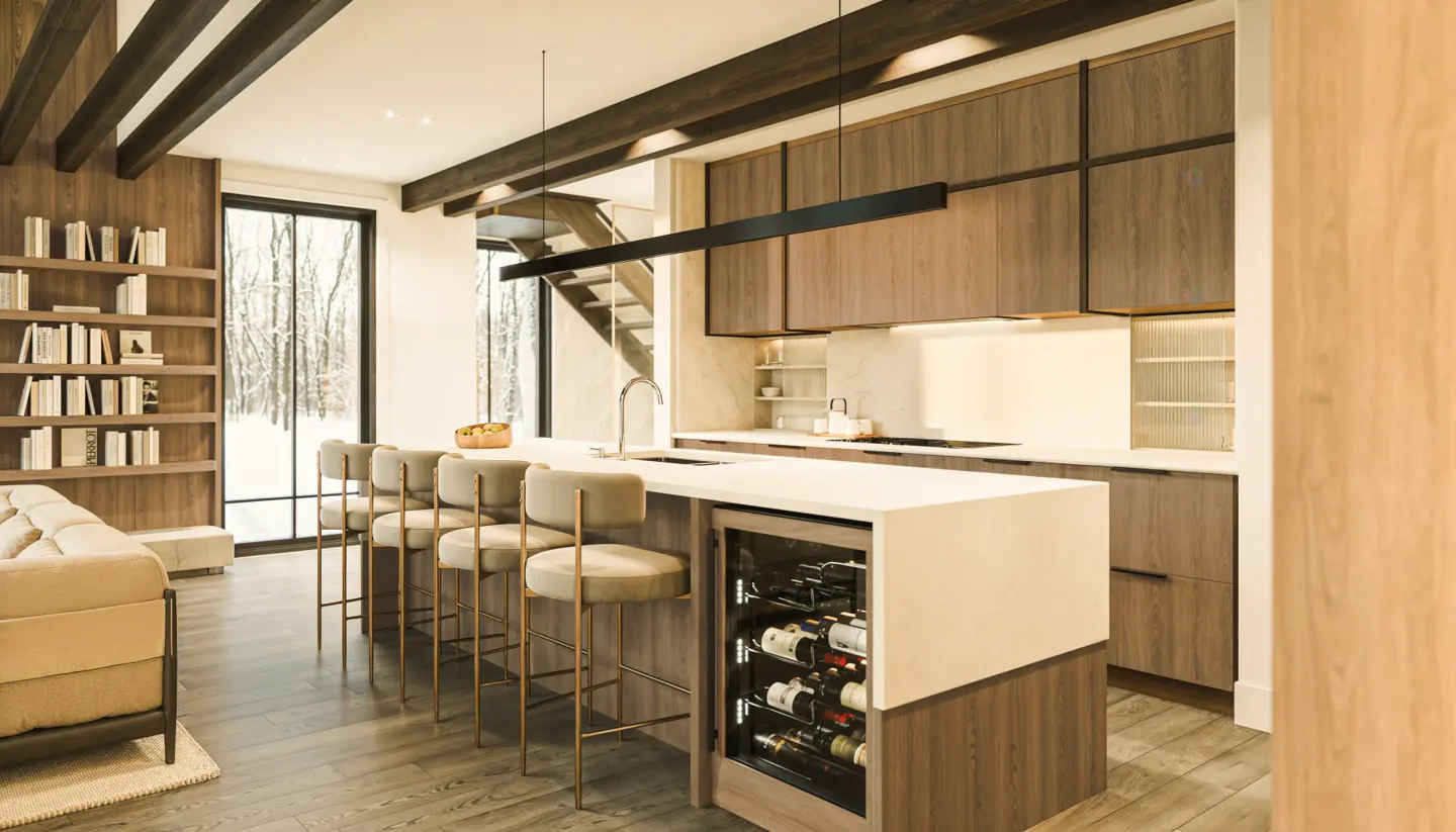 Modern kitchen with wood cabinets, white countertops, and island with wine fridge. Bar stools line the island. Bookshelf and snowy view in background.