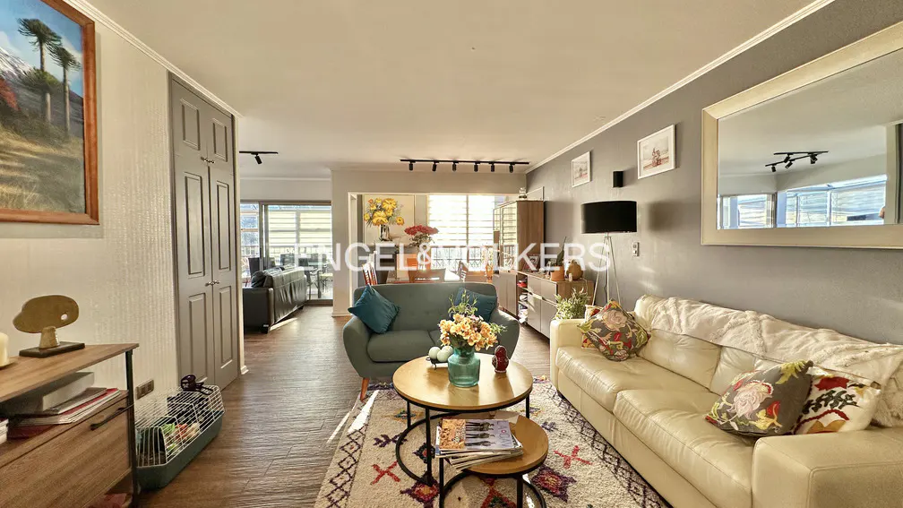 Living room with a green sofa, a white sofa, and a round coffee table on a patterned rug. A painting hangs on the wall.