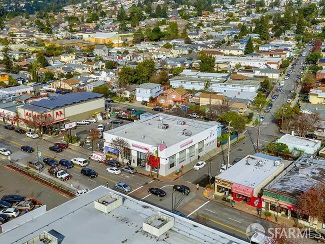 Aerial view of a busy street in a town with cars, buildings, and trees.