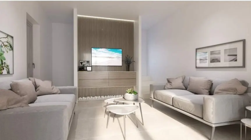 Bright living room with two gray sofas, a TV above a dresser, and three small tables.