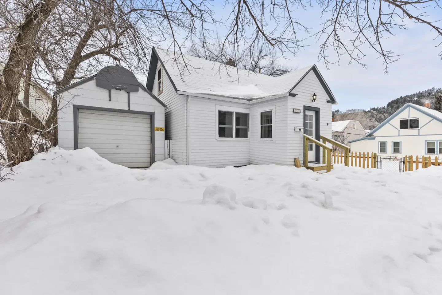 A white house and garage are covered in snow on a winter day.
