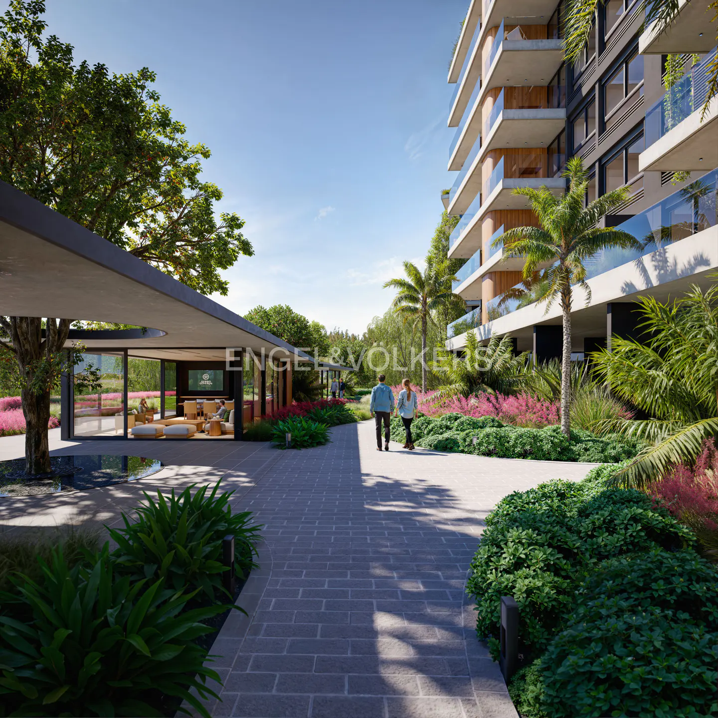 Exterior view of a modern apartment building with lush landscaping and a couple walking on a stone path. A lounge area is visible in the background.