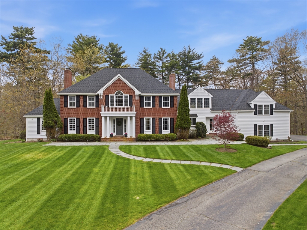 Two-story brick and white house with black shutters, a gray roof, and a green lawn.