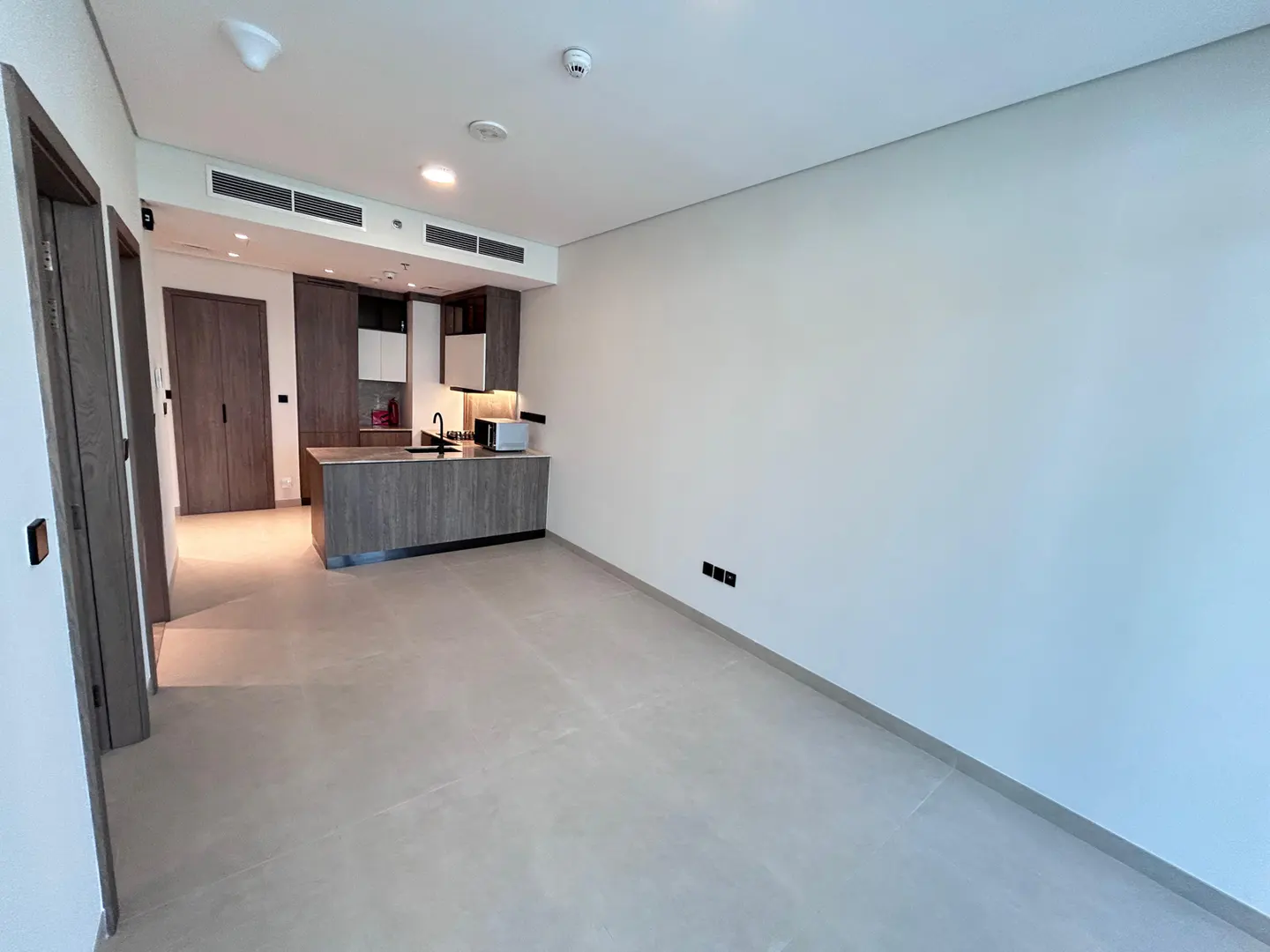 A bright, empty apartment with a gray kitchen island and white walls.