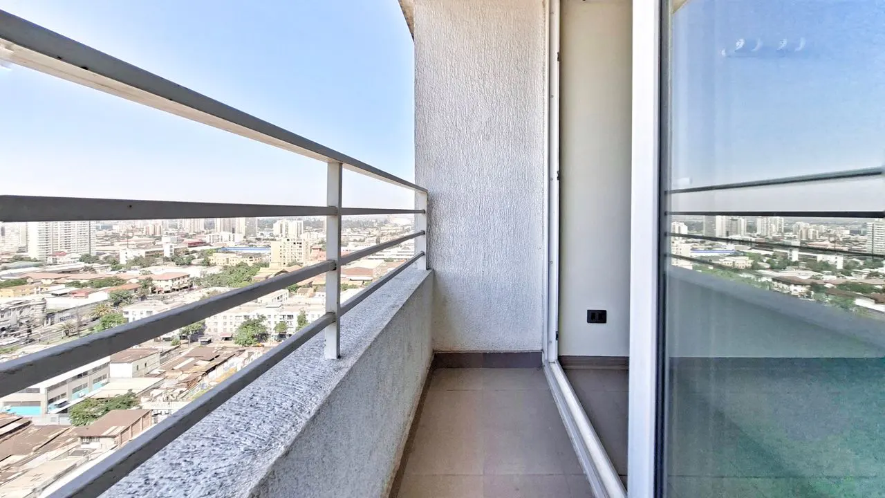 Balcony view of a city skyline. Gray metal railing, textured white wall, and open sliding glass door.