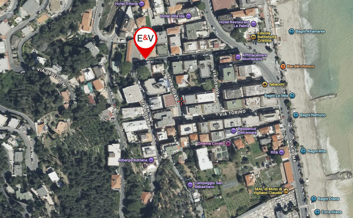 Aerial view of a coastal Italian town with a red "E&V" location marker near hotels and streets.