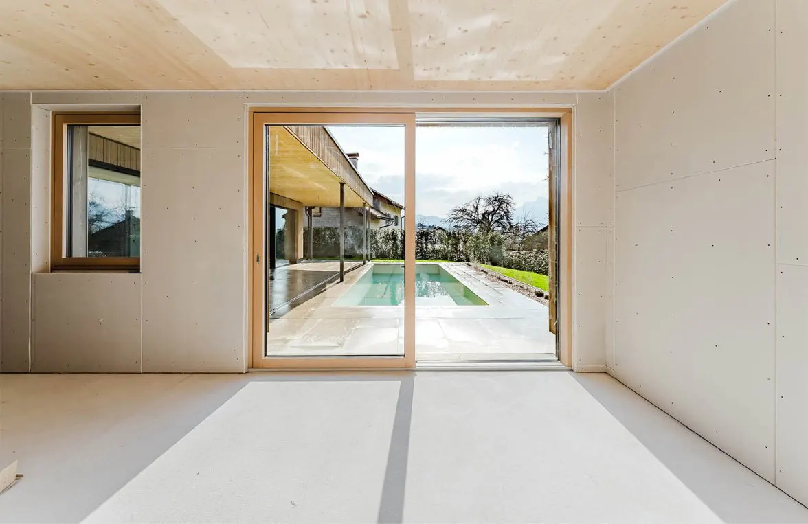 An unfinished room with a sliding glass door that opens to a pool and backyard.