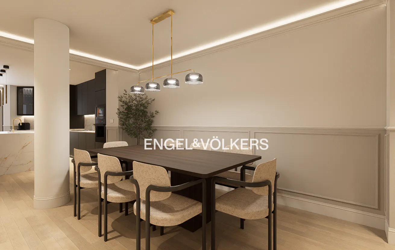 Modern dining area with a dark wood table, beige upholstered chairs, and a gold pendant light against paneled walls.