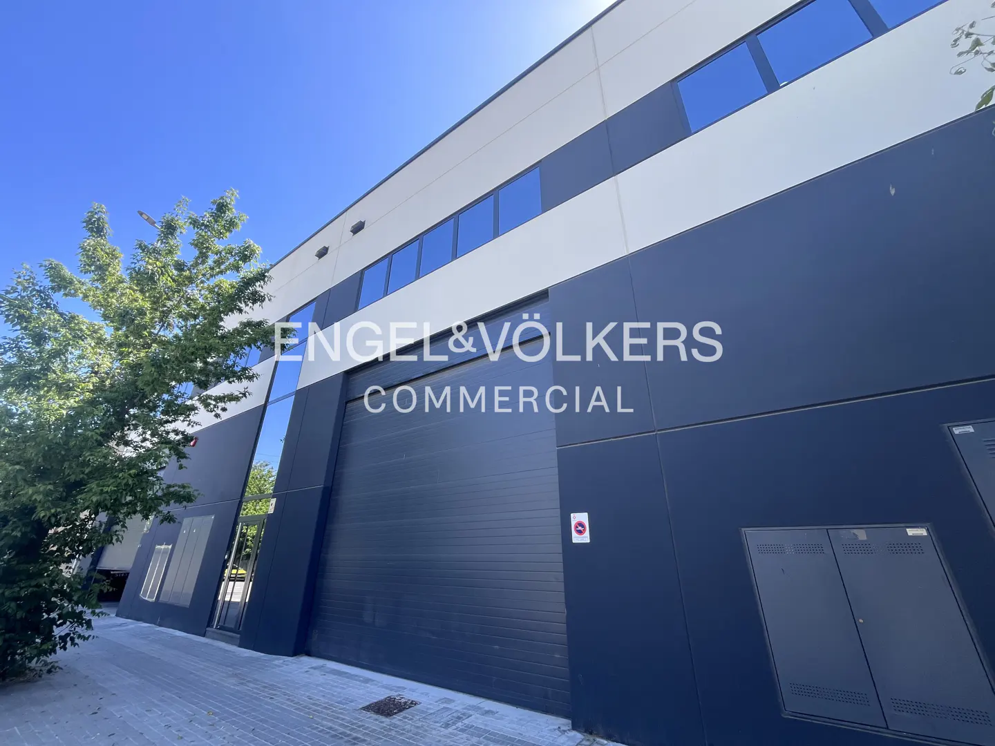 Exterior view of a two-story commercial building with blue windows and the Engel & Völkers logo.
