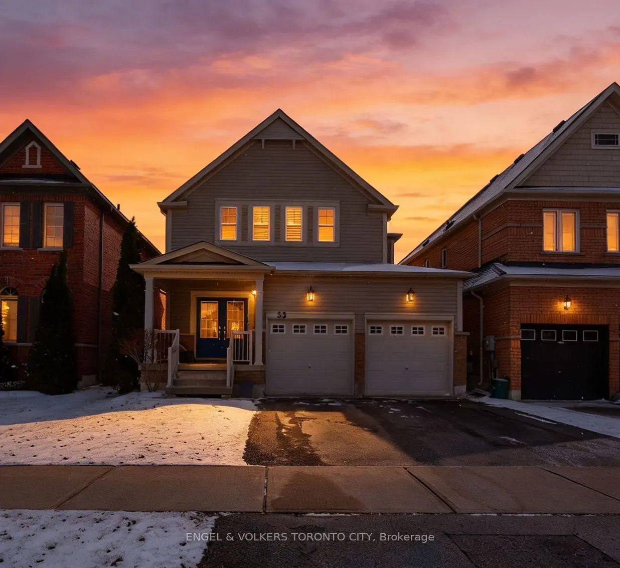 Two-story house with beige siding and a two-car garage at sunset. Snow on the lawn.