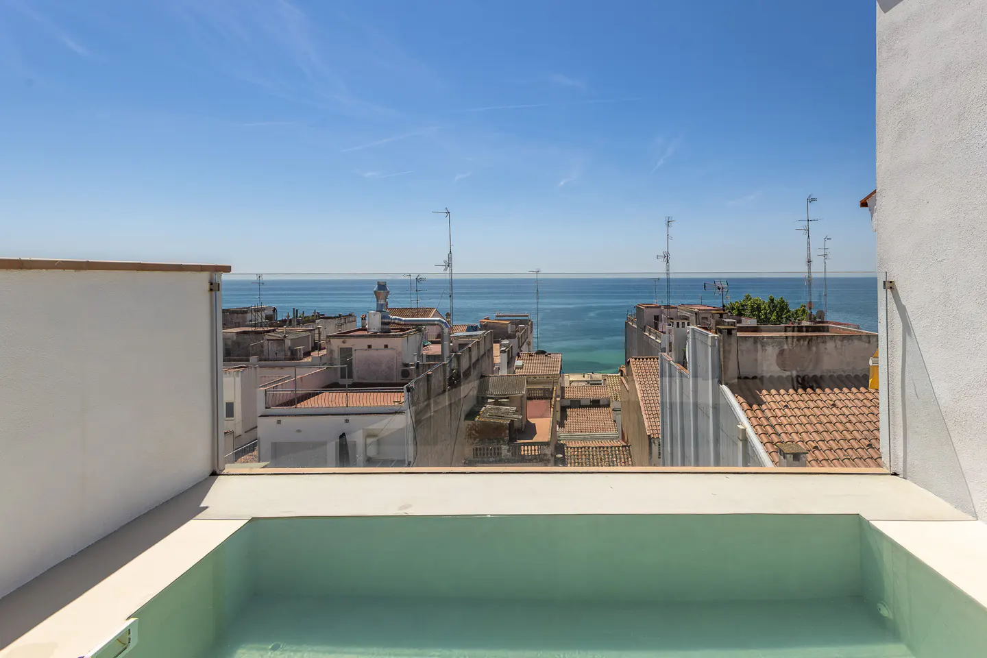 Rooftop pool with a view. Blue sky over the ocean and town with red tile roofs.