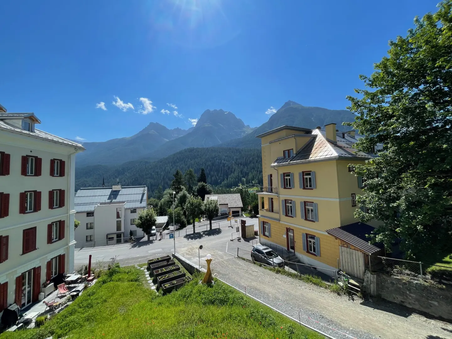 Scenic view of Swiss village with yellow and white buildings under a blue sky, mountains in the background.