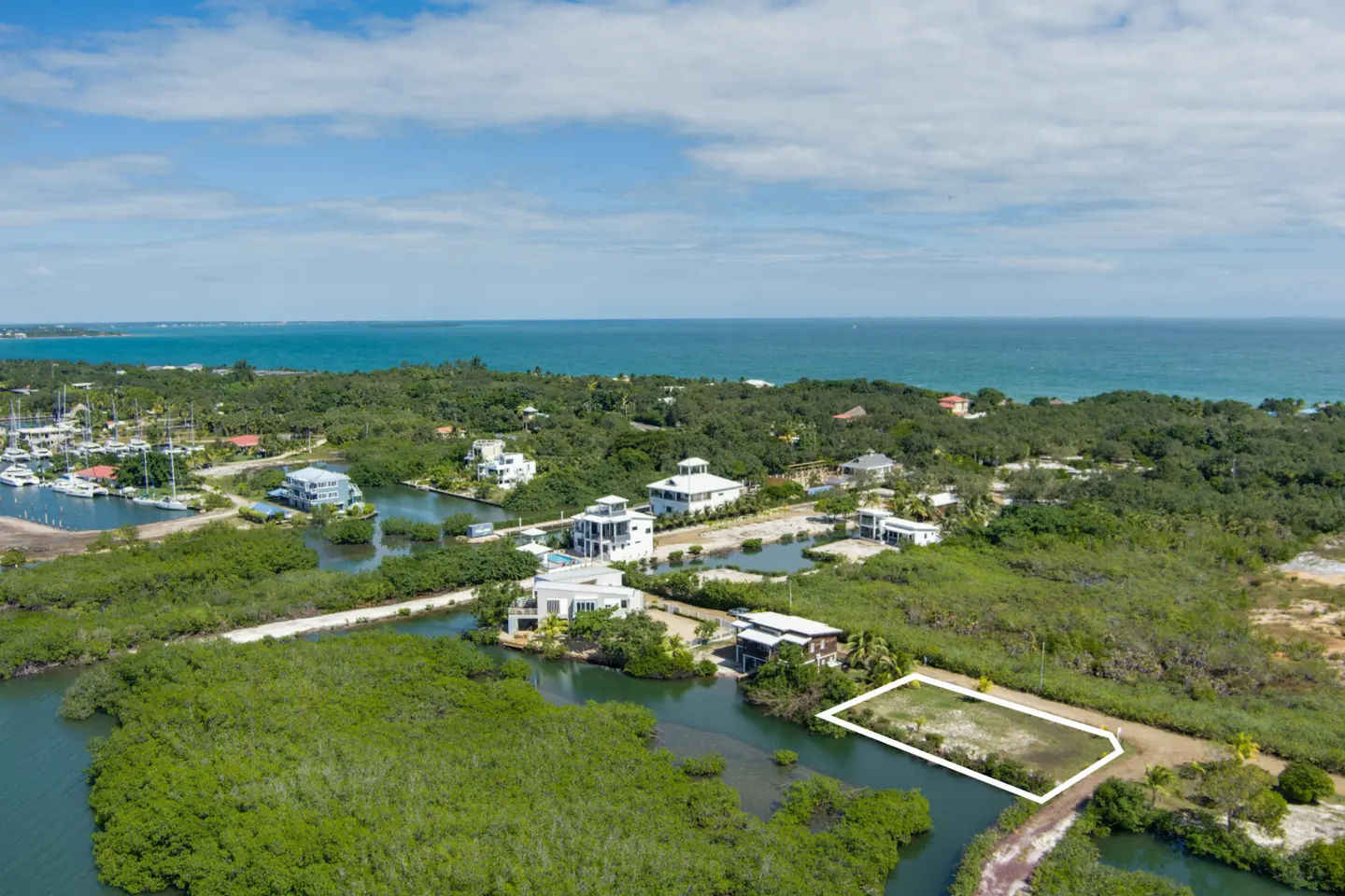 Aerial view of a waterfront property outlined in white, surrounded by lush green vegetation and waterways, with the ocean in the background.