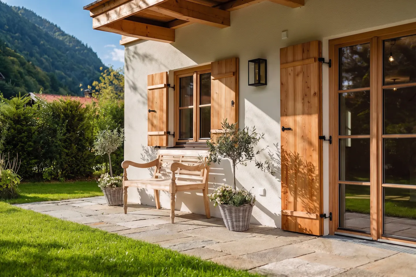 Exterior of a home with wooden shutters, a bench, and a mountain backdrop.