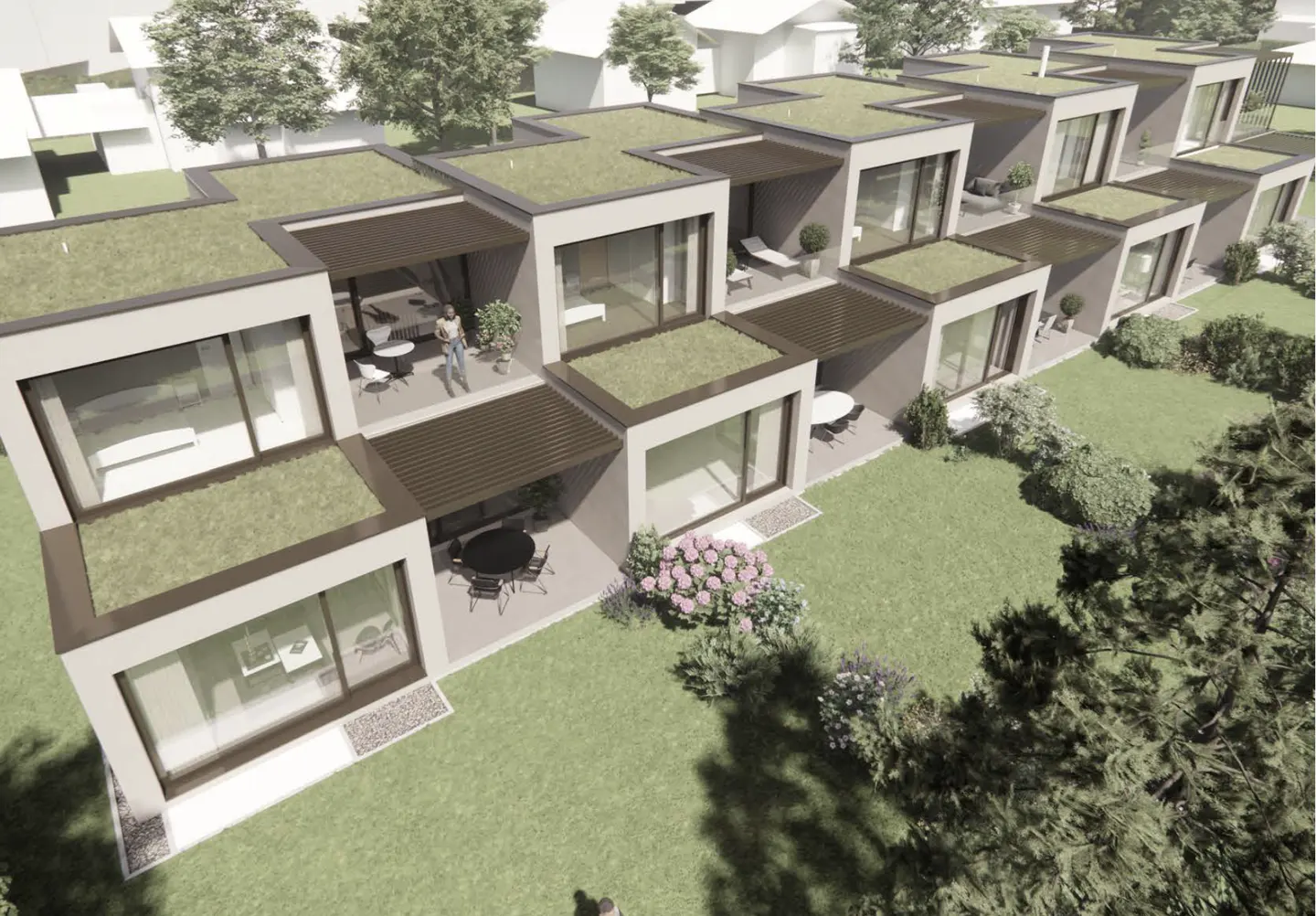 Aerial view of modern, cube-shaped homes with green roofs and patios. Landscaped yards with flowers and trees surround the houses.