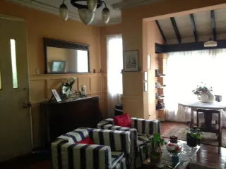 A living room with striped chairs, a dark wood table, and a round table with a white vase.