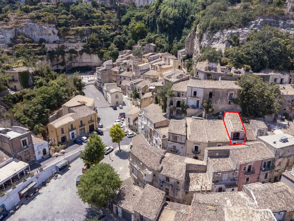 Aerial view of a European town with stone buildings and tile roofs, with a red outline around one building.