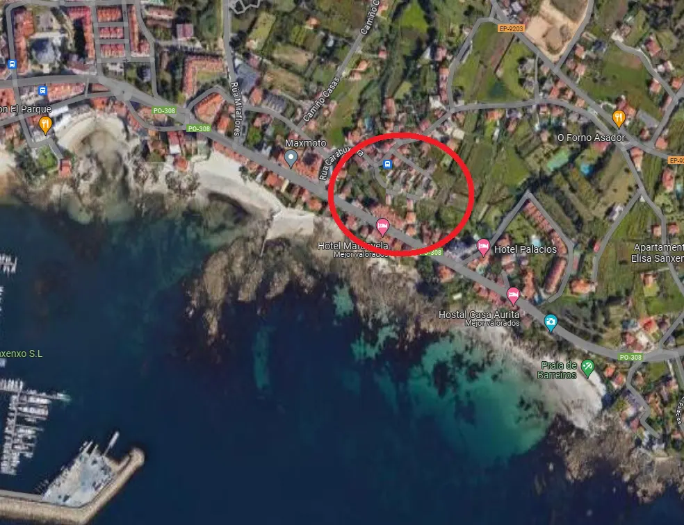 Aerial view of coastal town with red circle highlighting a residential area near the ocean.