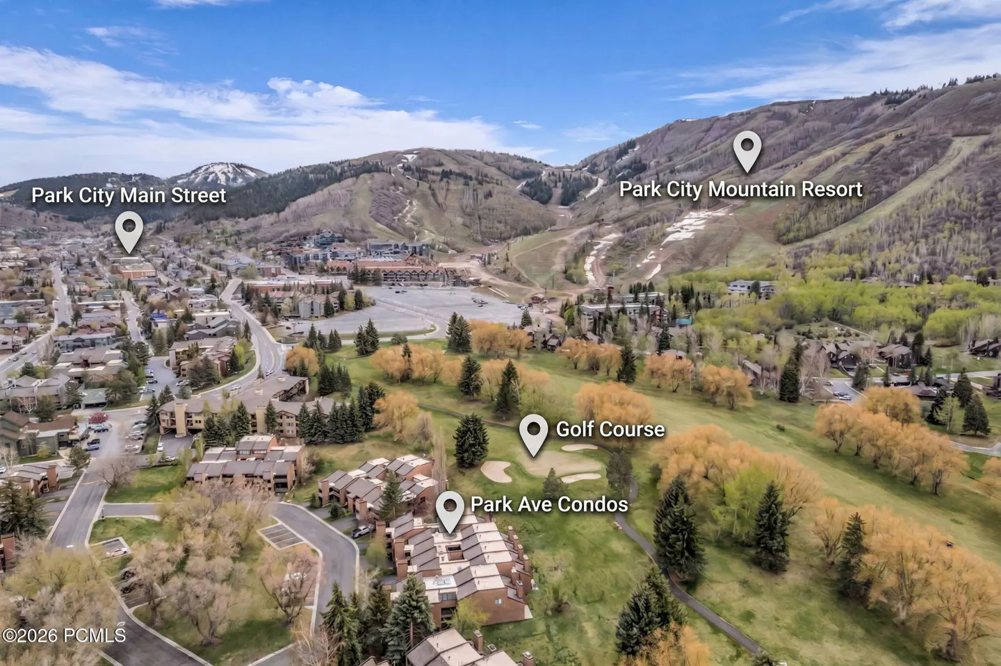 Aerial view of Park City, Utah, featuring condos, a golf course, and the mountain resort under a blue sky.