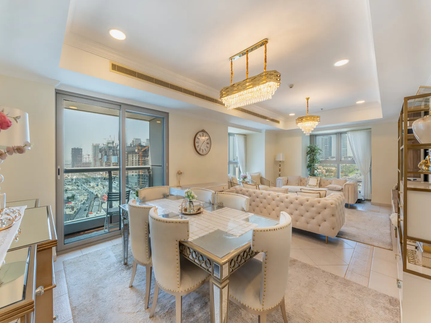 A bright, modern apartment interior with a dining table, chairs, and a view of the city skyline.