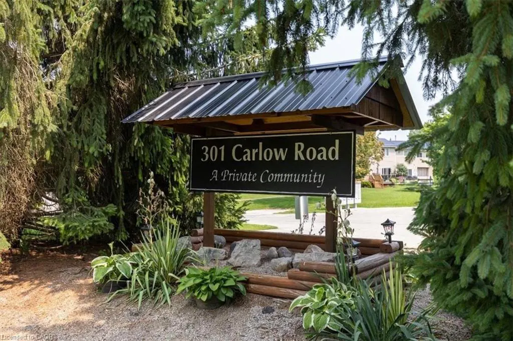 Entrance sign for "301 Carlow Road, A Private Community" with a dark roof, surrounded by greenery and landscaping.