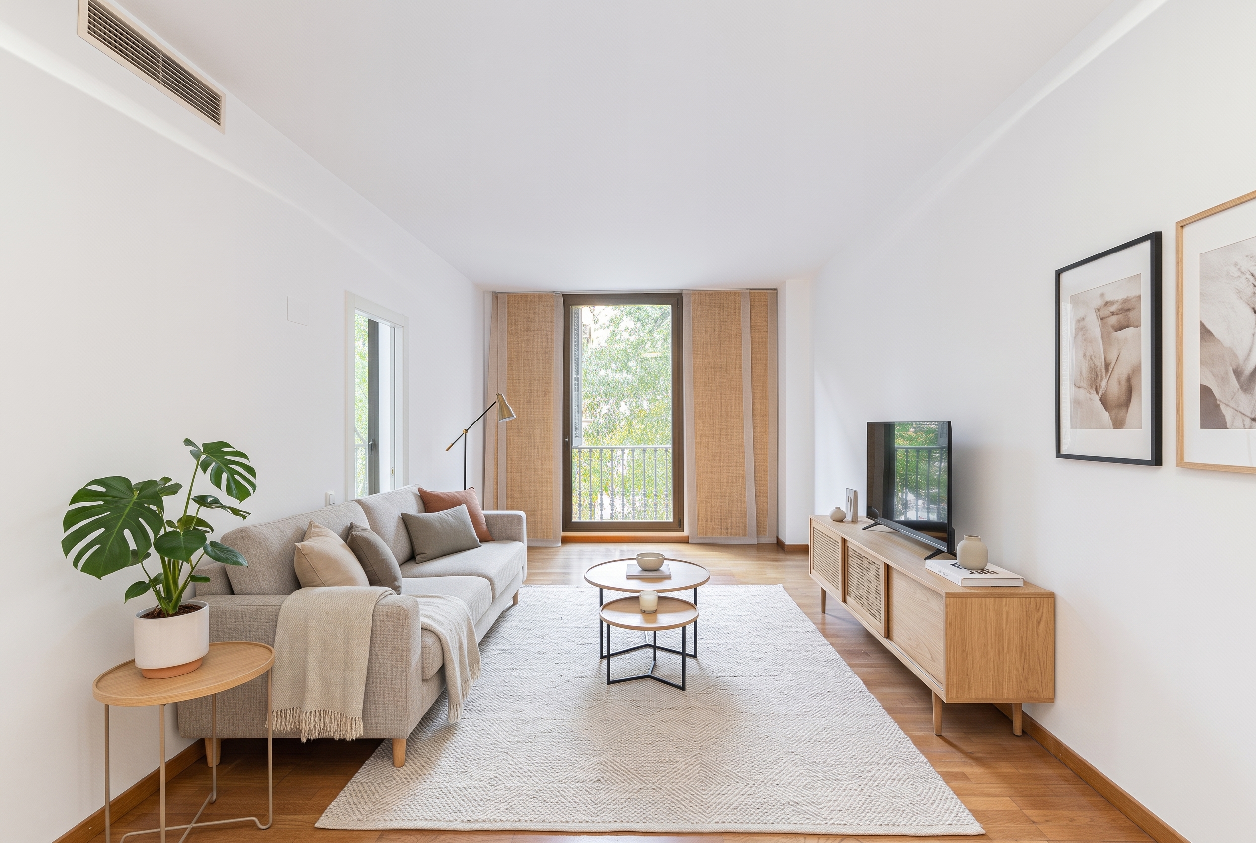 Modern living room with a beige sofa, wooden media console, two nesting coffee tables, and a large window with light curtains. [AI-generated text]