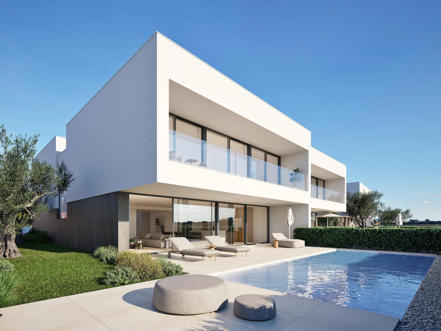 Modern white house with a pool. Lounge chairs sit on the patio. Blue sky.