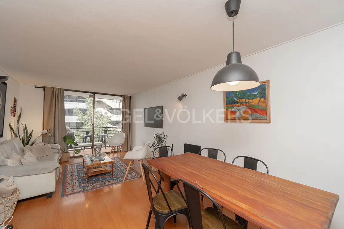 Bright living room with wood floors, a gray sofa, a wood table with black chairs, and a balcony with a view.