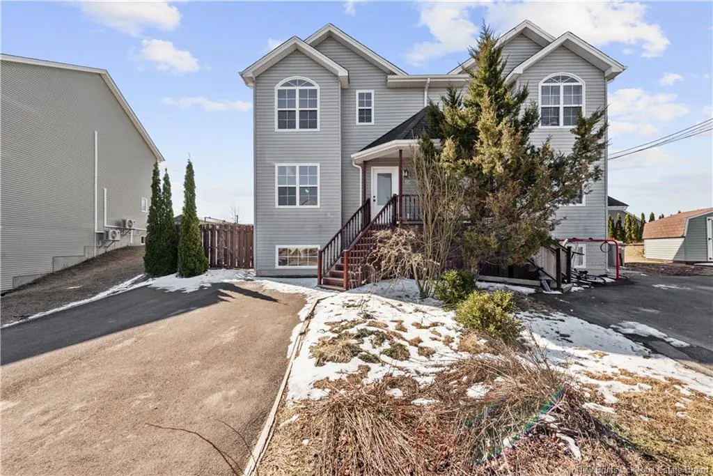 Two-story gray house with white trim and a brown staircase leading to the front door. A driveway leads up to the house.