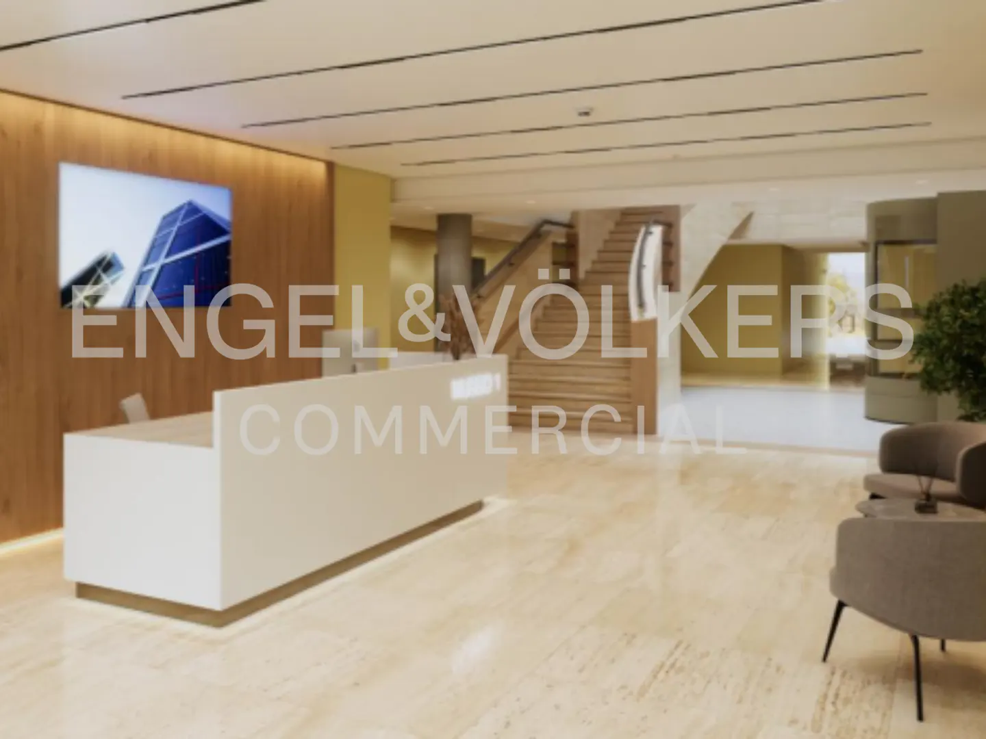 Engel & Völkers Commercial office lobby with a white reception desk, wood paneling, and seating area. Stairs lead to the upper level.