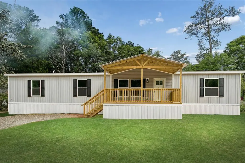 Exterior view of a single-story home with a covered porch, gray siding, black shutters, and a green lawn.
