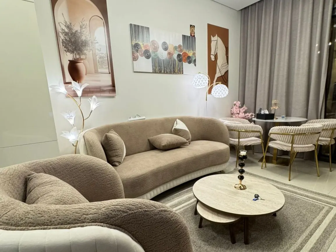 Living room with beige sofa, chairs, and rug. Artwork adorns the walls, and a unique flower lamp adds a touch of elegance.