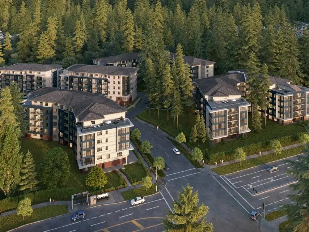Aerial view of modern apartment buildings with dark roofs, surrounded by lush green trees and a road with cars.