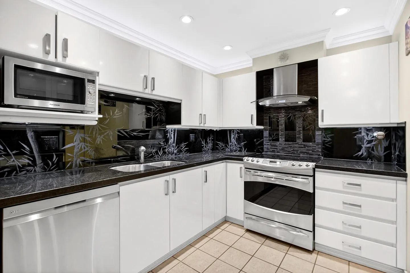 A modern kitchen with white cabinets, black granite countertops, and stainless steel appliances.