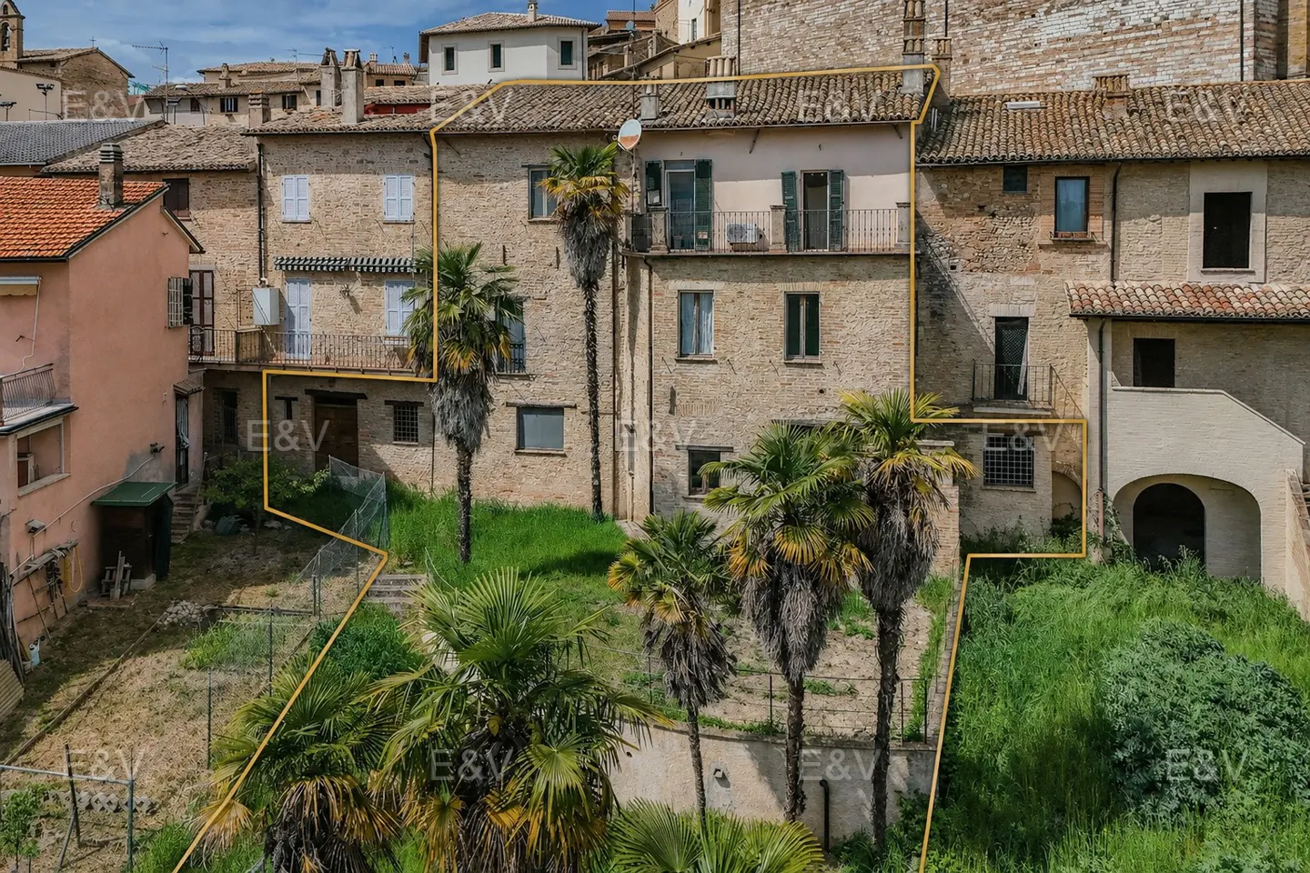 Exterior view of a multi-story brick building with balconies and palm trees, outlined in gold.