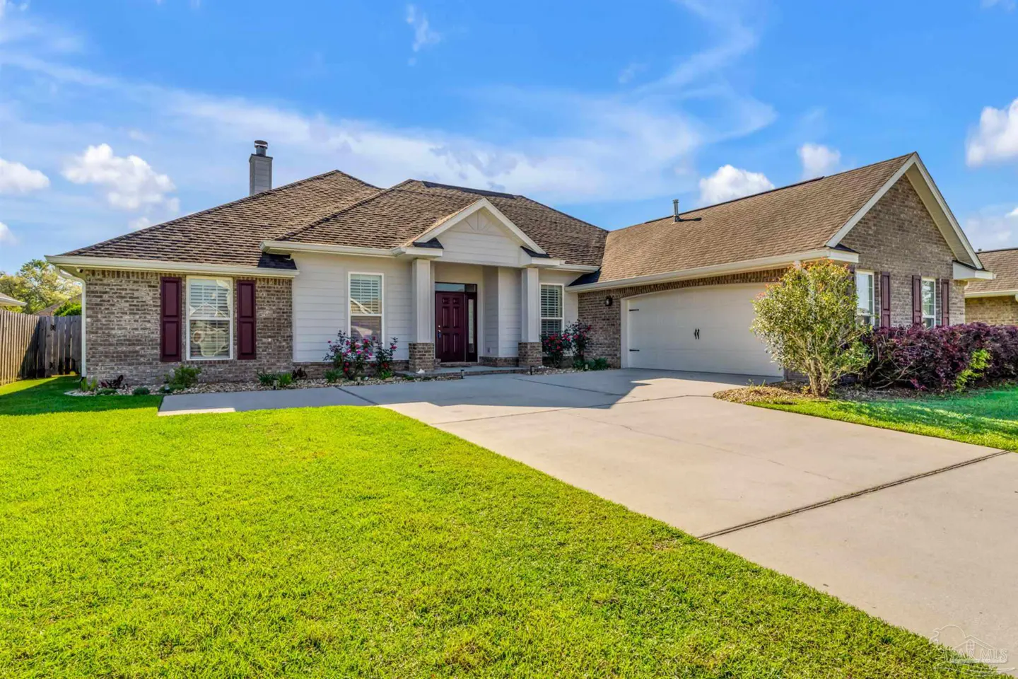 A single-story home with a brick and siding exterior, a brown roof, and a green lawn under a blue sky.