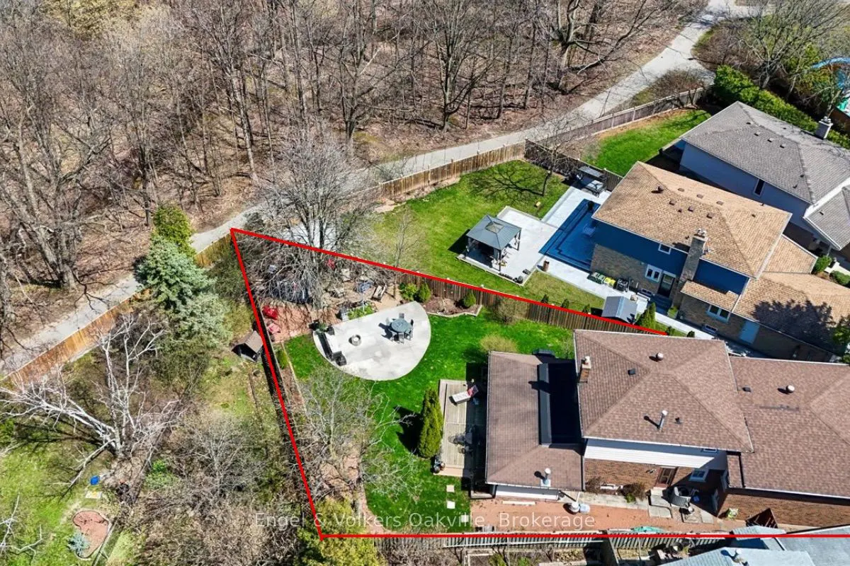 Aerial view of a property with a red boundary line, showcasing a green lawn, patio with furniture, and a pool area.