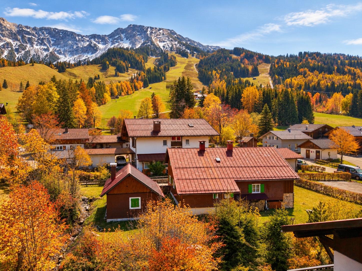 Alpine village with brown-roofed houses nestled in a valley surrounded by autumn trees and snow-capped mountains. [AI-generated text] [AI-modified]